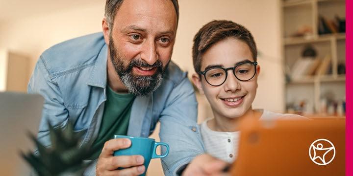 A father is helping his son on the computer